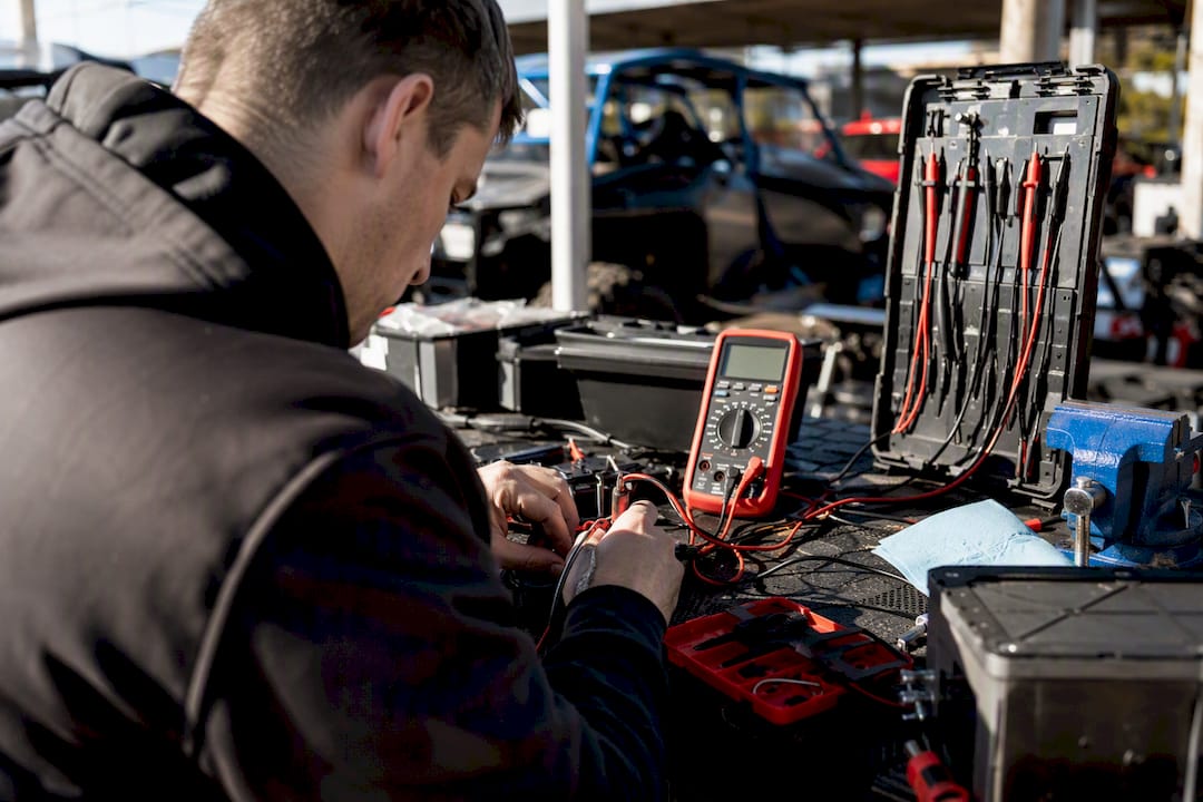 Hands testing lithium battery voltage