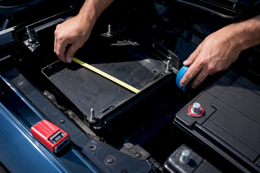 Hands measuring battery tray and terminals